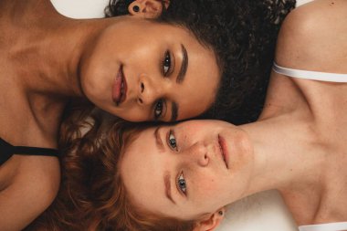 Photo of natural multiracial women, body positive. Feminist females lay down, isolated on white background. Concept natural beauty and girl power