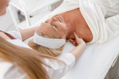 Son sınıf öğrencisi kadın sırt üstü uzanıyor, yüz masajı yaptırıyor. Yüz masajı güzellik tedavisi. Sağlık, güzellik ve rahatlama konsepti