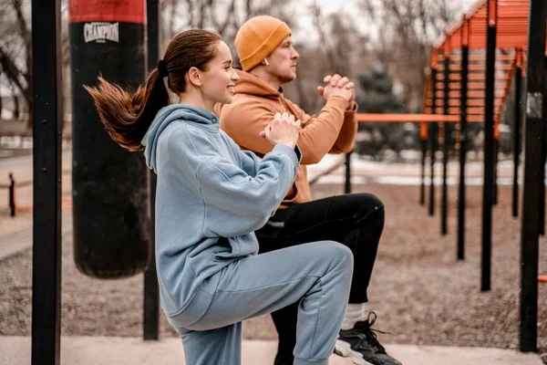 Spor kıyafetli genç bir çift sabah sporunu dışarıda yapıyor. Genç adam ve kadın sokak sporları alanında koşmadan önce kaslarını esnetiyorlar. Formda ve sağlıklı konsept.