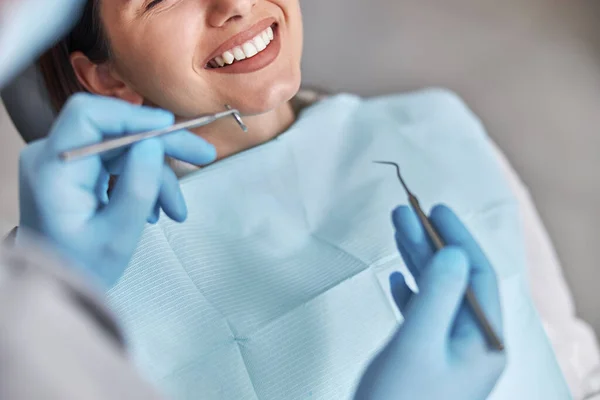 Neşeli dişçi ve dişçi müşterisi. Diş tedavisinde kadın hasta, modern diş kliniğinde diş aletleri kullanan doktor.