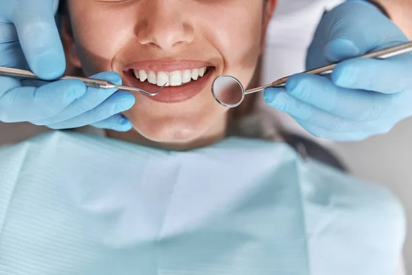 Neşeli dişçi ve dişçi müşterisi. Diş tedavisinde kadın hasta, modern diş sağlığı kliniğinde diş aletleri kullanan doktor. Kapatın..