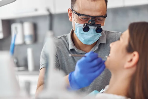 Cirurgia dentária moderna, rosto de uma médica a trabalhar num paciente. Operação de implantação dentária em um paciente em consultório odontológico — Fotografia de Stock