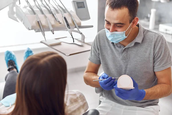 Dentista positivo alegre e cliente em odontologia. Olham um para o outro e sorriem. Cliente feminino senta-se na cadeira — Fotografia de Stock