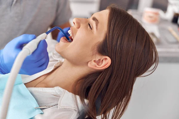 Paciente feminina no procedimento odontológico, médica usando instrumentos dentários na clínica odontológica moderna, de perto. — Fotografia de Stock