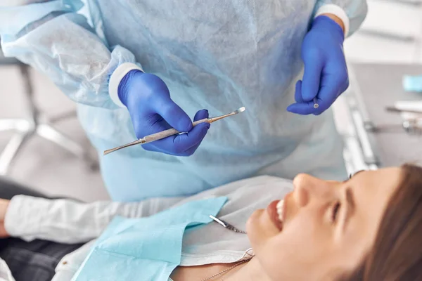 Retrato de jovem dentista em luvas examinando dentes de cliente feminino no hospital — Fotografia de Stock