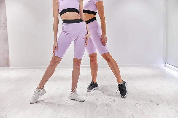 Två kvinnliga idrottare som sträcker på benen och tränar. Intensiv konditionsträning på loft industrigym — Stockfoto