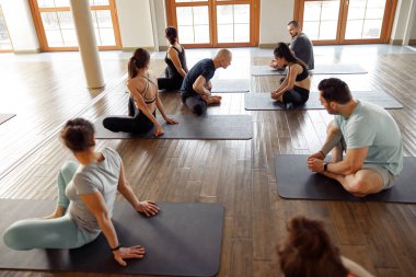 Öğretmen yoga sınıfında öğrenci rehberliği yapıyor. Modern spor kulübünde yoga yapan genç sporcular.