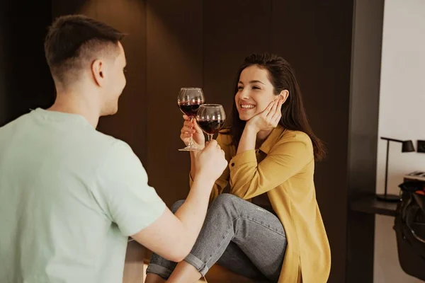 Прекрасна пара з келихами вина має романтичну вечерю вдома. Щаслива молода сім'я переїхала в нову квартиру — стокове фото
