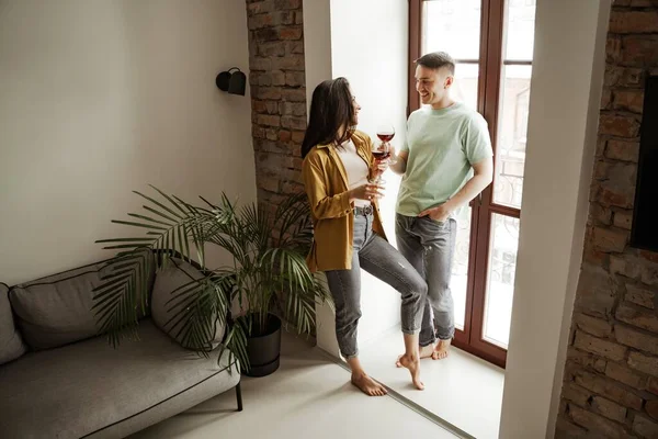 Preciosa pareja con copas de vino en casa, vibraciones románticas. Familia joven feliz se mudó a nuevo apartamento — Foto de Stock