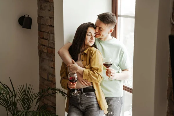 Casal encantador com copos de vinho em casa, vibrações românticas. Jovem família feliz mudou-se para novo apartamento — Fotografia de Stock