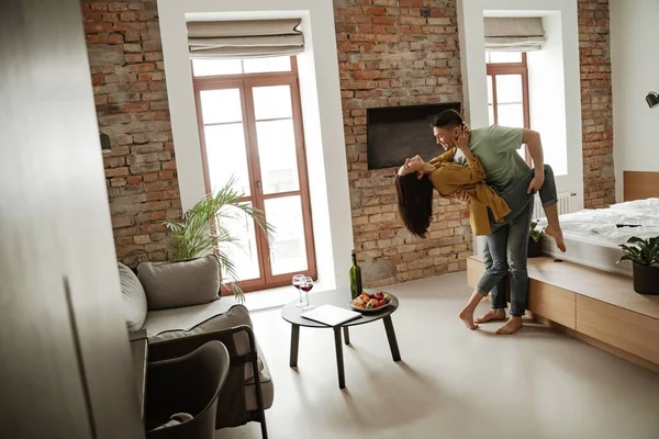 Feliz pareja joven está bailando y mostrando sus sentimientos en un piso nuevo. Preciosa familia mudándose a nuevo apartamento — Foto de Stock