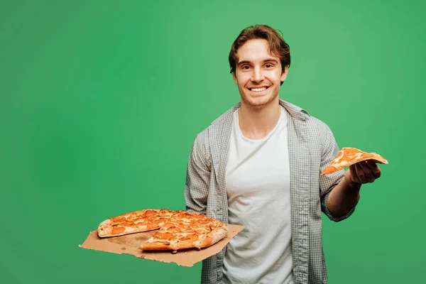 Aardige man houdt pizza en voel je gelukkig, geïsoleerd op groene achtergrond — Stockfoto