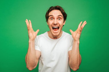 Genç adam şaşırmış ve mutlu görünüyor, yeşil arka planda soyutlanmış.