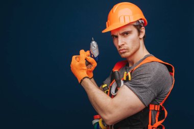 Çekici müteahhitin kolunda silah gibi ekipman var, mavi arka planda izole edilmiş.