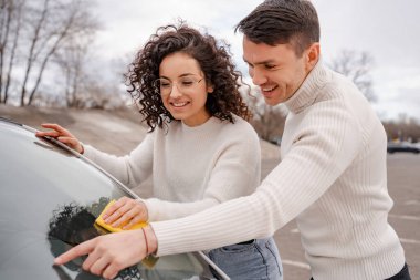 Avrupalı çift arabanın ön camını paçavrayla temizliyor