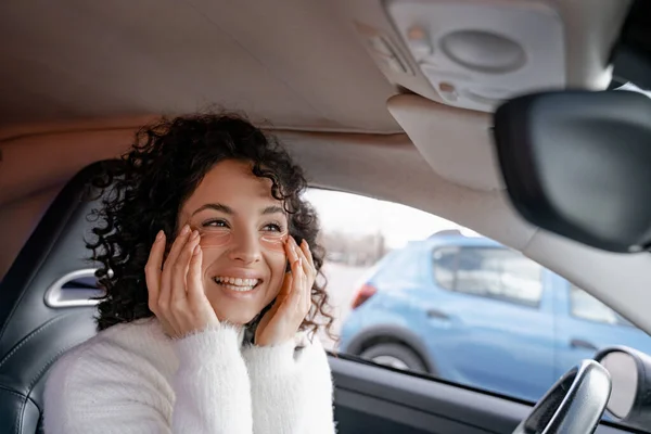 Дівчина дивиться під оком на обличчі в дзеркалі автомобіля — стокове фото