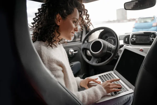 Європейська дівчина в автомобілі друкує ноутбук. — стокове фото