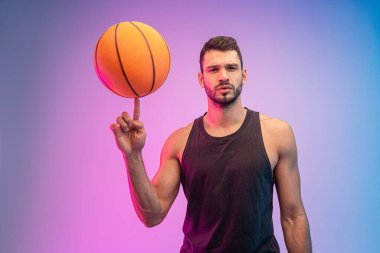 Genç sporcu parmak üstünde basketbol topu çeviriyor.