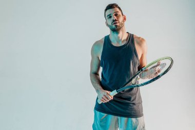 Kendinden emin erkek tenisçi raketle poz veriyor.