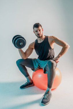 Stüdyoda dambılla bisepsi çalıştıran sporcu.