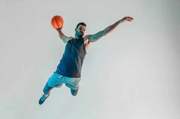 Sporcu zıplayıp basketbol topu atmak istiyor.