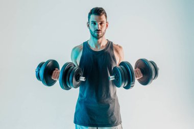 Genç adam kaslarını halterle çalıştırıyor.