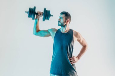 Genç adam dambılı omuz kaslarını çalıştırıyor.