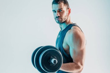 Genç adam kaslarını halterle çalıştırıyor.