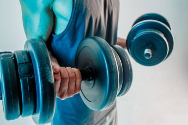 Genç adam kaslarını halterle çalıştırıyor.