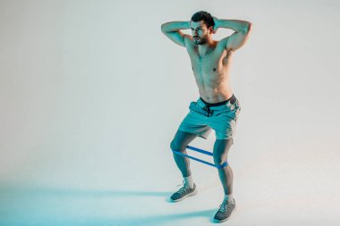 Genç sporcu direniş bandıyla bacak çalıştırıyor.