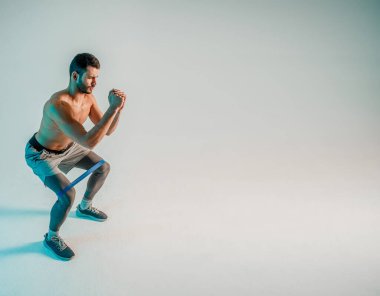 Genç sporcu direniş bandıyla bacak çalıştırıyor.