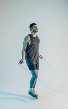 Ciddi genç sporcu ip atlayarak atlıyor.