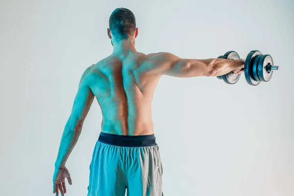 Hombre joven entrenando los músculos del hombro con mancuerna — Foto de Stock