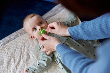 Annem yeni doğmuş bir bebeğin ağzına emzik veriyor.