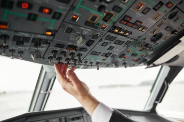 Erkek pilot yolcu uçağının düğmesini çeviriyor