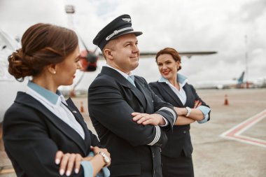 Pilot ve hostesler uçak jetine yakın pistte.