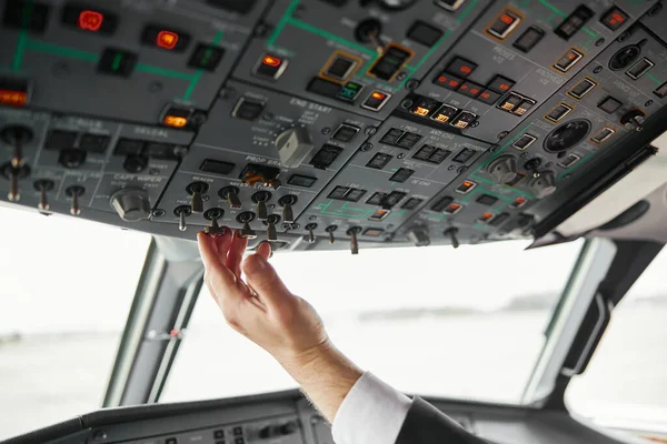 Male pilot turning button on passenger airplane — Stock Photo, Image
