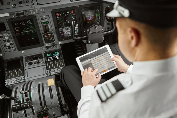 Пилот использует цифровой планшет в пассажирском самолете — стоковое фото
