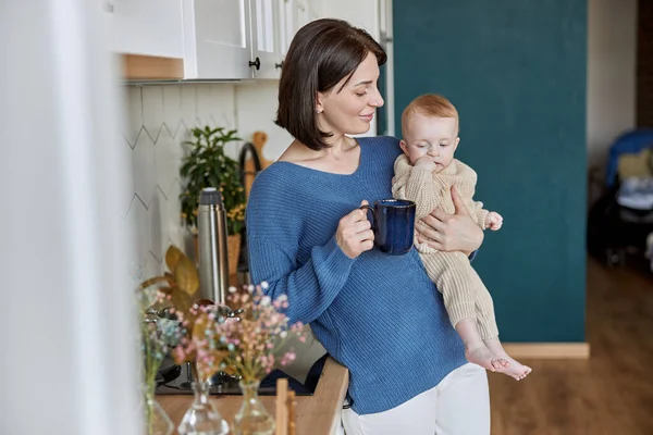 Mujer sosteniendo a su bebé recién nacido y taza con té Imagen De Stock