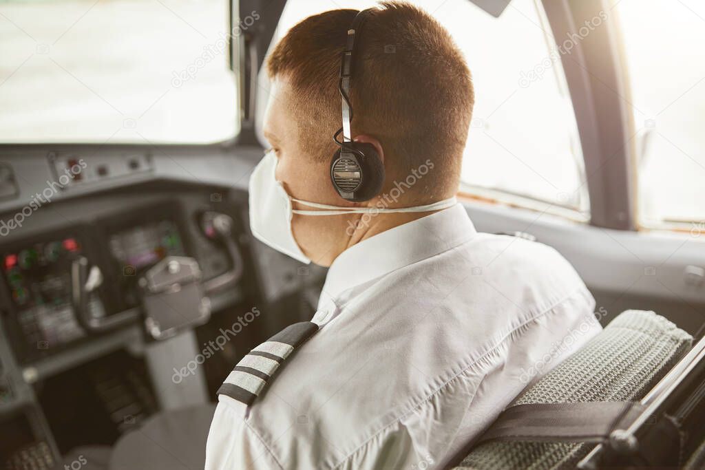 Male pilot in cockpit of passenger airplane jet