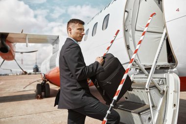 Uçuş görevlisi merdivenle uçağa çıkıyor.