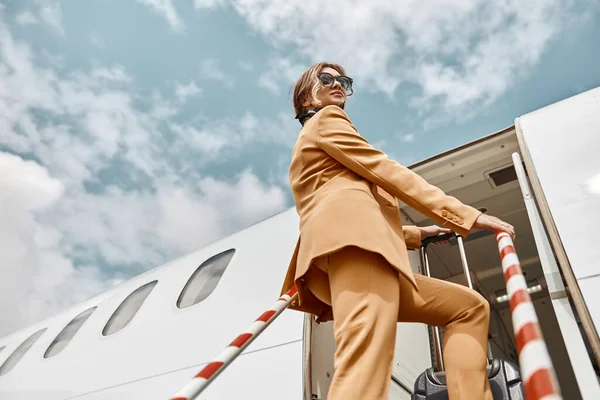 Бизнесмен идет с багажом на лестнице к самолету — стоковое фото