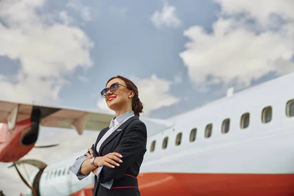 Улыбающаяся стюардесса на взлетно-посадочной полосе возле самолета — стоковое фото