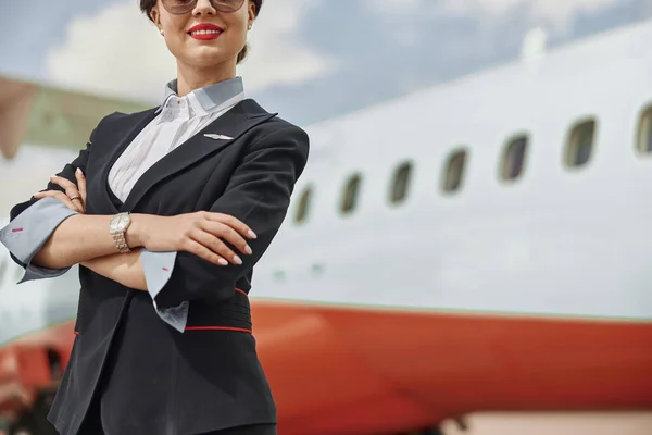 Улыбающаяся стюардесса на взлетно-посадочной полосе возле самолета — стоковое фото