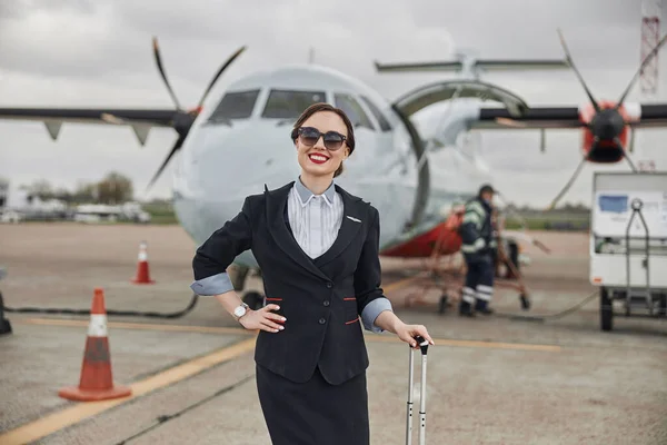 Aeromoça com bagagem na pista perto do avião — Fotografia de Stock