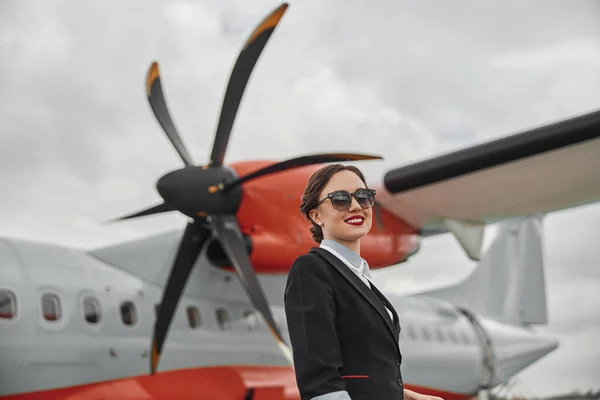 Молодая стюардесса на фоне реактивного самолета — стоковое фото