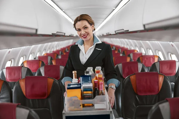 Letuška s jídelním vozíkem v kabině letadla — Stock fotografie