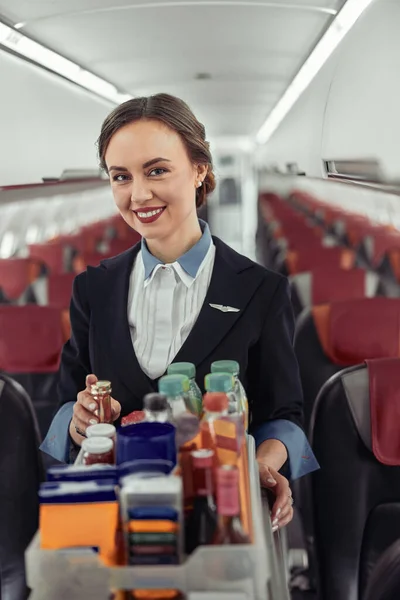 Letuška nesoucí jídelní vozík v kabině letadla — Stock fotografie