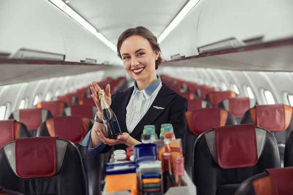 Letuška show láhev s alkoholem v letadle — Stock fotografie