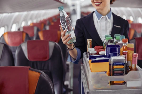 Azafata sosteniendo botella de agua en cabina de avión — Foto de Stock